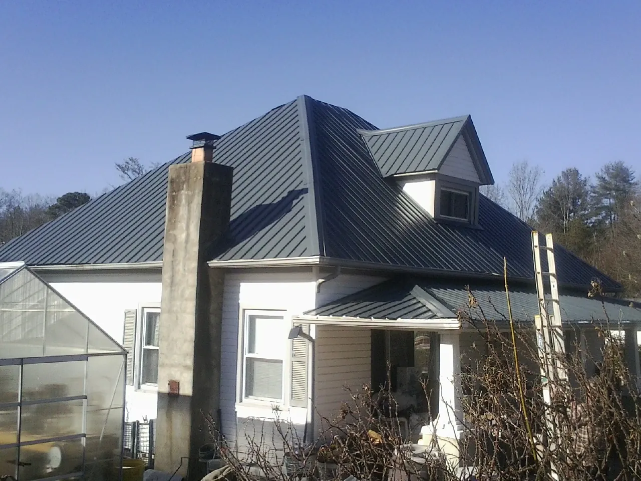 Dark blue standing seam metal roof on a white farmhouse with dormer in Playa Vista