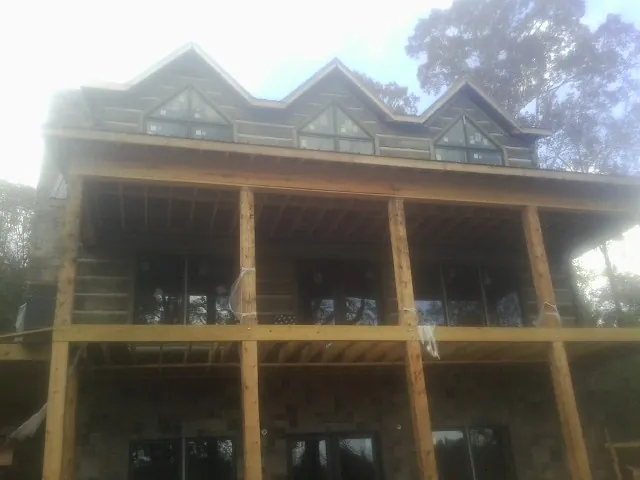 Dormers and porch framing on a large log home under construction — Roof Coating work by our crew in Playa Vista