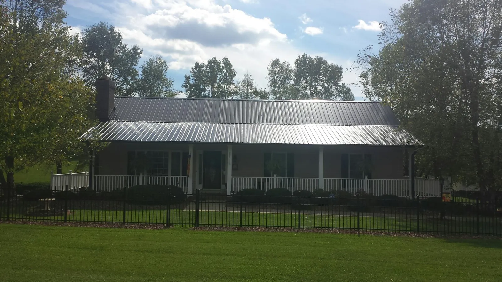 Gray metal roof on a brick ranch with a full width front porch — Gutter Guard Installation work by our crew in Playa Vista
