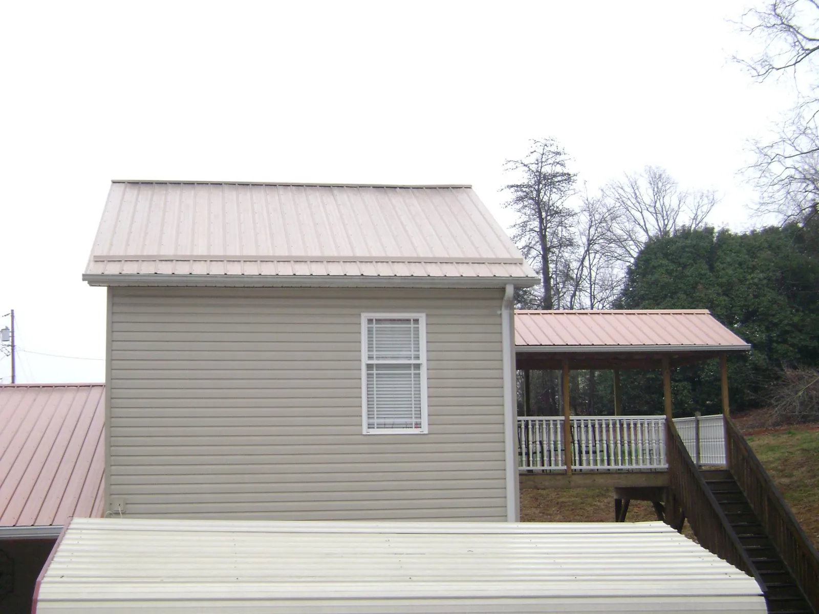 Tan metal roofs on a two story addition and attached porch, from a Roof Replacement job in Playa Vista